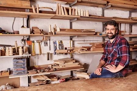 坐在木制品工作室做肖像的工匠照片